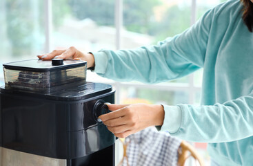 Beautiful woman making coffee in kitchen, closeup