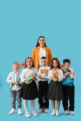 Little school children with female teacher on light blue background