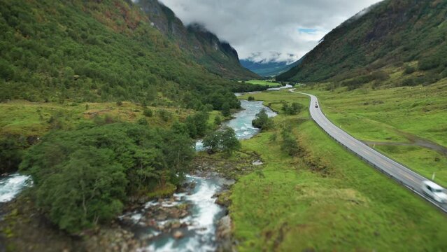 A E39 road winds along the river through the green Myklebustdalen valley. Aerial view,  fast forward.