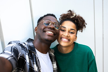 Happy African American young couple taking selfie looking at camera. Relationship and love