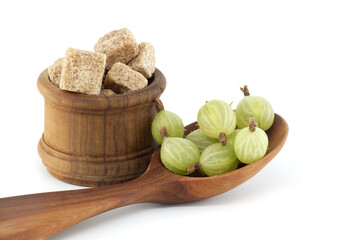 Gooseberries in a wooden spoon and sugar cubes