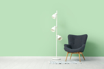 Comfortable armchair and floor lamp near color wall