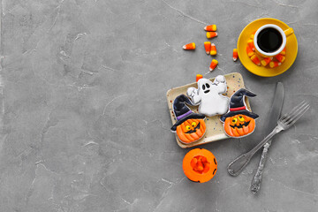 Plate with tasty cookies, candy corns and cup of coffee for Halloween celebration on grey background