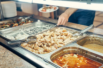 Distribution of food in the dining room. Self-service, a person puts food on his own plate choosing what he wants, selective focus. High quality photo