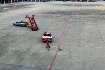 Airplane tow tractor at the airport apron near the terminal. Aircraft Towing Tractor. A towing tractor belonging in air port is being operated by officer. Aerodrome tow tractor is driving at airport