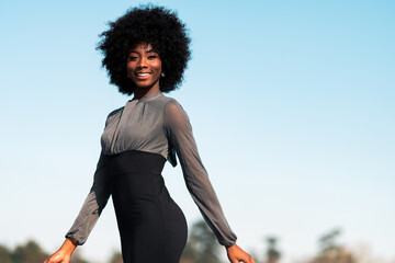 mujer afroamericana sonriente caminando por las calles, haciendo poses, modelando al aire libre con...