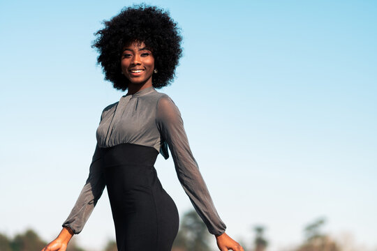 mujer afroamericana sonriente caminando por las calles, haciendo poses, modelando al aire libre con minifalda