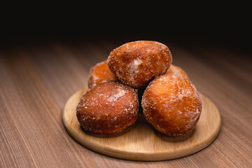 Several bakery dreams placed on top of a wooden board, surrounded by powdered sugar