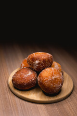 Several bakery dreams placed on top of a wooden board, surrounded by powdered sugar