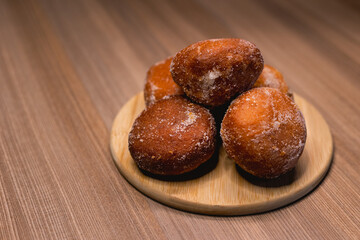 Several bakery dreams placed on top of a wooden board, surrounded by powdered sugar