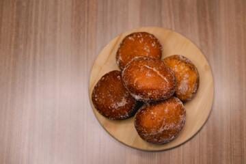 Several bakery dreams placed on top of a wooden board, surrounded by powdered sugar