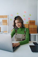 Starting small business entrepreneur of independent young Asian woman online seller is using computer and taking orders to pack products for delivery to customers. SME delivery concept