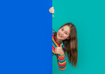 happy girl behind blank blue paper with copy space for advertisement. thumb up