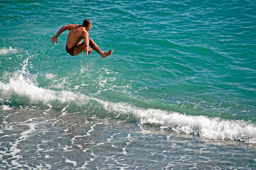 Amalfi, Amalfi Coast, Salerno, Campania, Italy, Europe - happy young man jumping to waters of Adriatic sea  after fast run on the beach, March