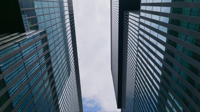 Upwards abstract dolly view of shiny exterior of skyscrapers against sky