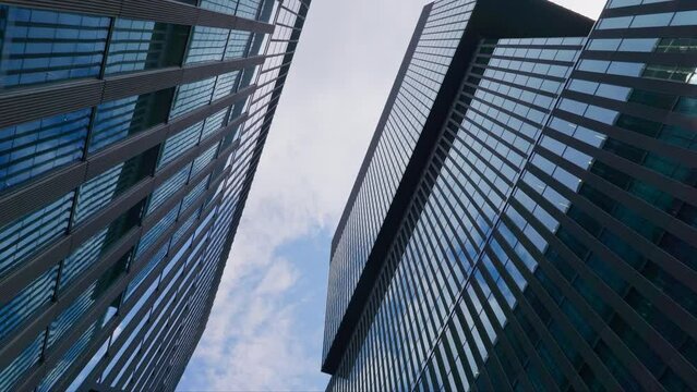 Upwards view between tall modern office buildings, reflective window exteriors