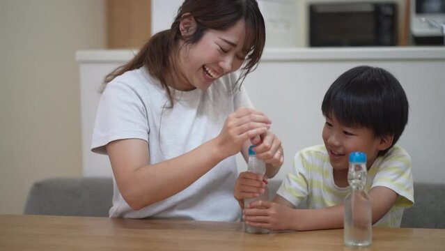 ラムネ瓶のビー玉を落とす親子