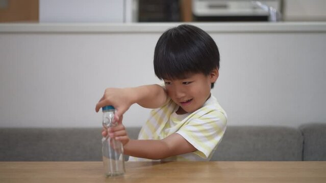 ラムネの瓶からビー玉を取り出そうとする男の子