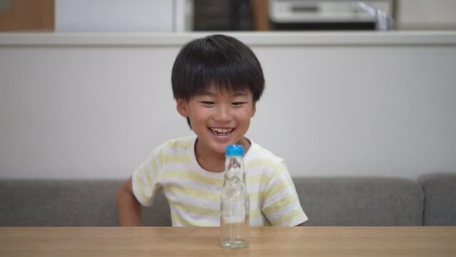 ラムネの瓶からビー玉を取り出そうとする男の子