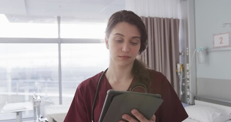 Portrait of happy caucasian female doctor using tablet in hospital room, slow motion