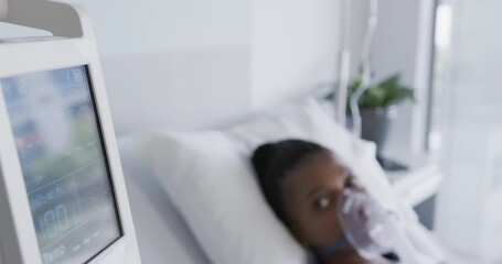 African american female patient with oxygen mask lying in bed in hospital room, slow motion - Powered by Adobe