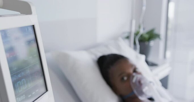 African american female patient with oxygen mask lying in bed in hospital room, slow motion
