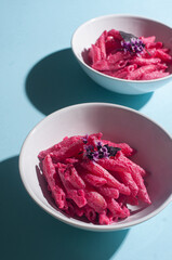 Delicious trendy pink beetroot pasta on minimalist blue background recipe copy space stylish flat lay