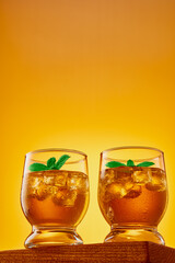 Two glasses of refreshing iced tea with ice cubes and mint leaves. Copy space. Studio shot from a low angle.