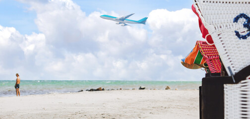 Beach panorama with wicker beach chair . Airplane in the blue sky with clouds from below, high...