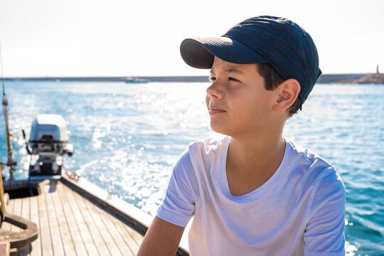 Handsome young boy on a boat smiling during regata on a sea or river.