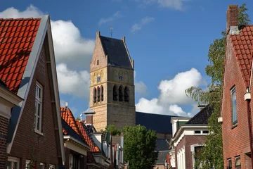 Fototapeten The bell tower of Martinikerk (St Martin church) viewed from Kerkstraat street in Bolsward, Friesland, Netherlands, with colorful house facades in the foreground © Christophe Cappelli