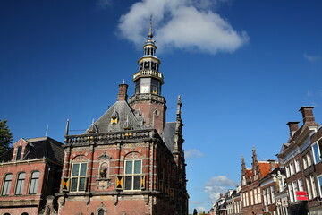The ornate and colorful architecture of Renaissance style City Hall of Bolsward, Friesland, Netherlands, with historic house facades on the right