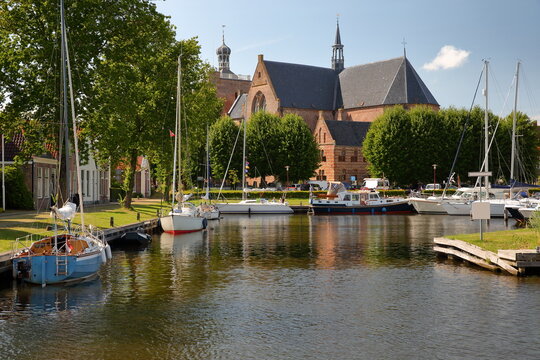 Grote or Gertrudiskerk (Greater or St Gertrude Church) in Workum, Friesland, Netherlands, with boats mooring in the foreground