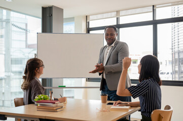 A professional African American businessman training Asian employees and briefing project.