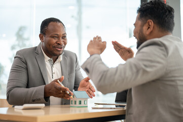 A professional African-American male real estate agent is having a meeting with his Asian client