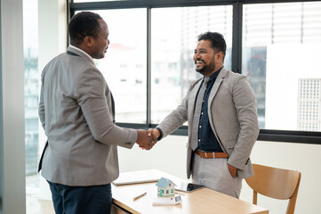 A professional Indian-Asian businessman shakes hands with an African American business partner