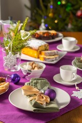  Coffee table setting with white tableware in Christmas style on a table with a purple tablecloth. Merry Christmas concept. Receiving guests,