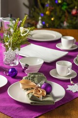  Coffee table setting with white tableware in Christmas style on a table with a purple tablecloth. Merry Christmas concept. Receiving guests,