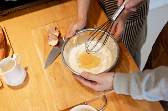 Close-up top view image of a couple mixing pancake flour in a mixing bowl