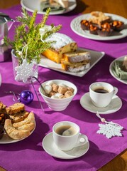  Coffee table setting with white tableware in Christmas style on a table with a purple tablecloth. Merry Christmas concept. Receiving guests,