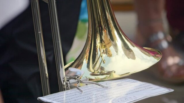 Detailed view of a trombone and its sheet music while played at a parade, recorded in decelerated speed.