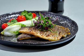 Fried seabass fillet with vegetables in a plate
