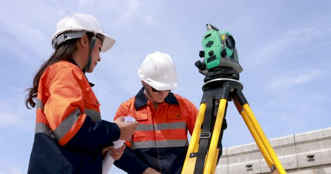 Engineer use theodolite equipment and looking blueprints construction project for route surveying to build a bridge across the intersection to reduce traffic congestion during rush hours.4k video
