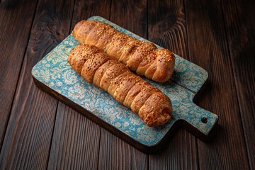 Sausage in dough, meat bun on brown boards. For decoration of bakery sales outlets. Bakery products. Fresh bakery.