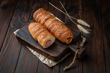 Sausage in dough, meat bun on brown boards. For decoration of bakery sales outlets. Bakery products. Fresh bakery.