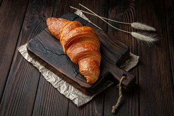 Delicate fluffy ruddy croissant with butter on brown boards. Bakery products. Fresh bakery.