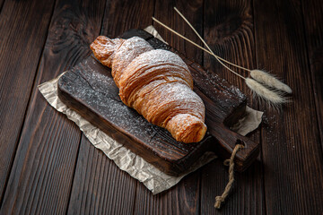 Delicate fluffy ruddy croissant with butter on brown boards. Bakery products. Fresh bakery.