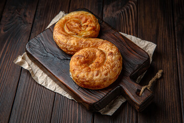 Lush puff pastry with potatoes, cottage cheese, cabbage, or meat on brown boards. Bakery products. Fresh bakery.