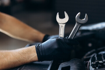 Car mechanic holding wrench for car repair