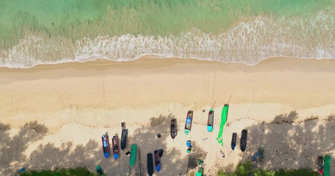 aerial view White foam waves in the green sea lapping on the white sandy beach..fishing boats parking on the white sand beach..sea waves crashing on shore background
